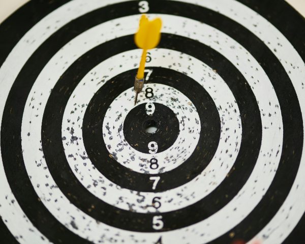 pexels-photo-1552617-1552617 Close-up of a dart hitting the bullseye on a black and white target board symbolizing success.