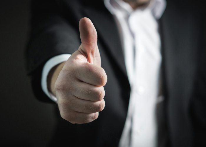 A close-up of a man's thumbs up gesture, symbolizing success and agreement.